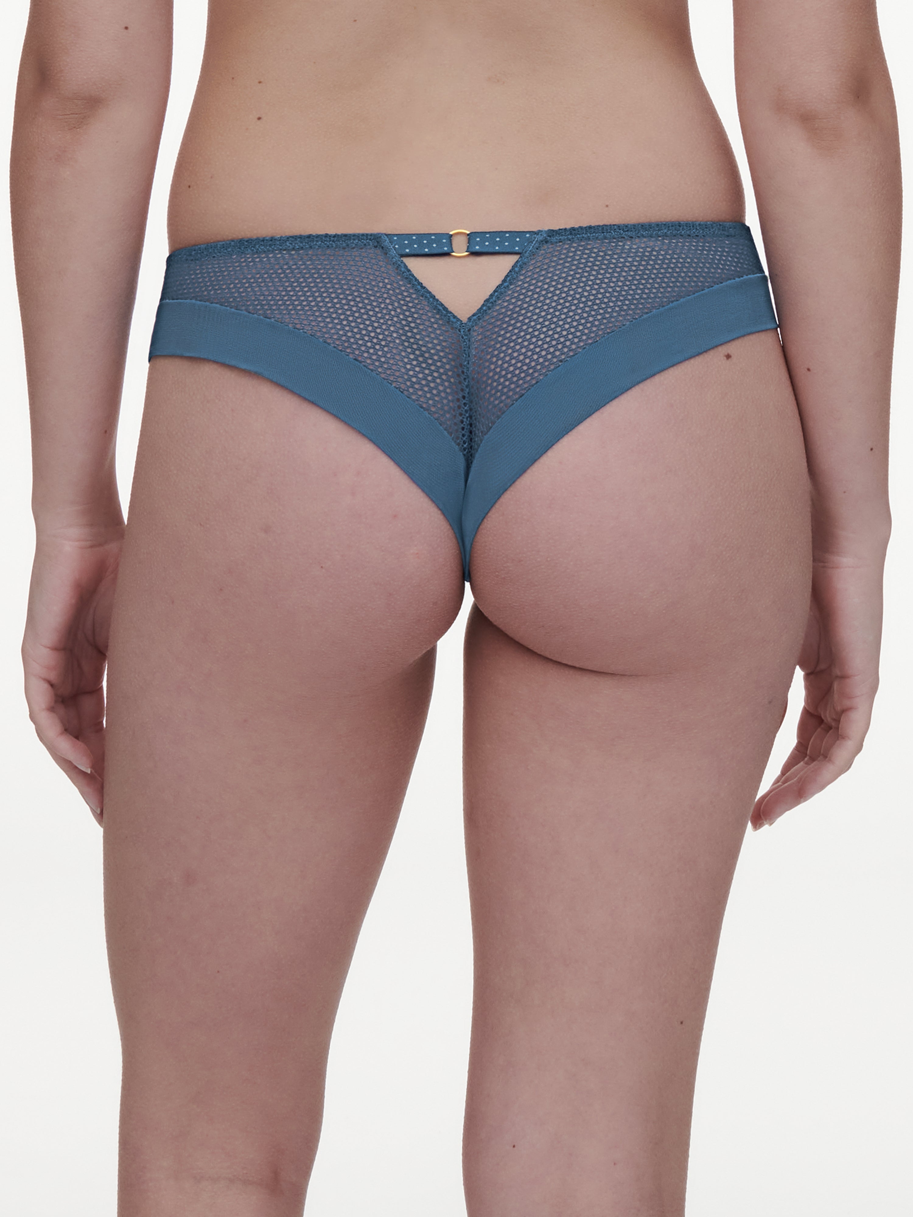 Back view of the Fleurs Signature Lace Thong in Blue Denim, showcasing a seamless design, a V-shaped cutout with a jewel accent, and sheer mesh panels for a flattering fit.